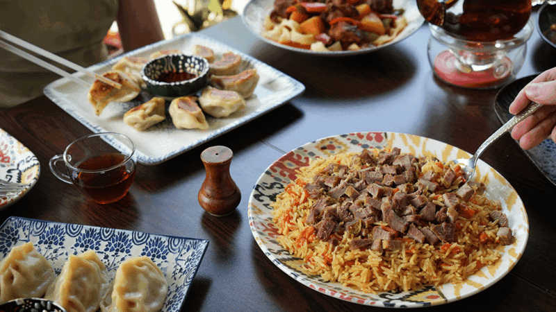 Deux personnes mangent un plat de polo ouïghour et de benchir sautées
