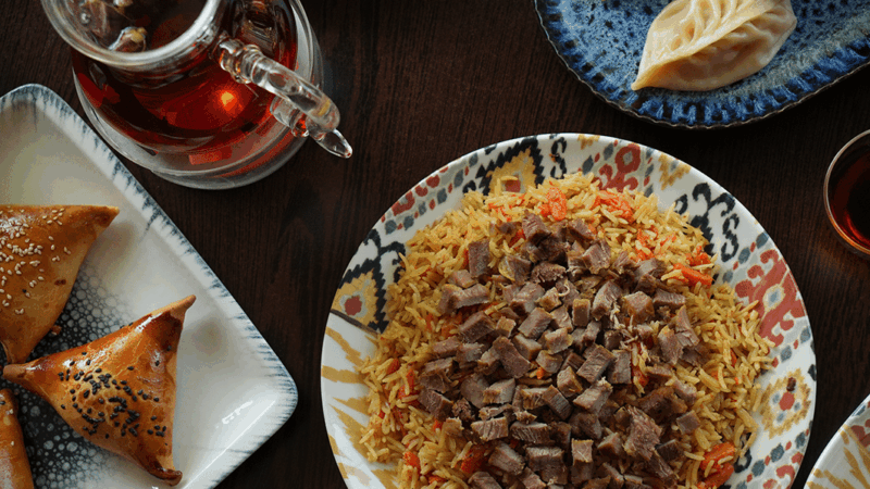 Table de plats de polo ouïghour, de samsas, de mantas et de thé